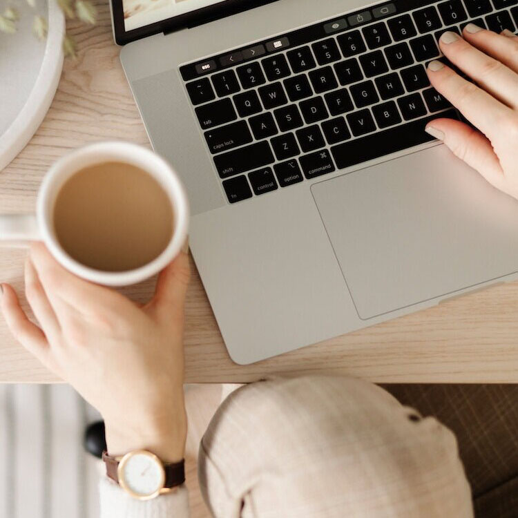 Tasse Tee neben dem Laptop.